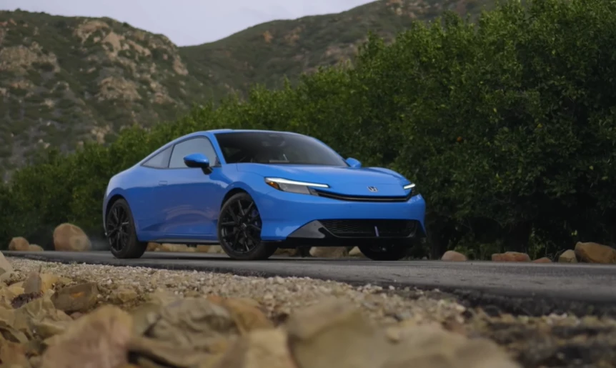 Side profile of 2025 Honda Prelude Hybrid driving on mountain road