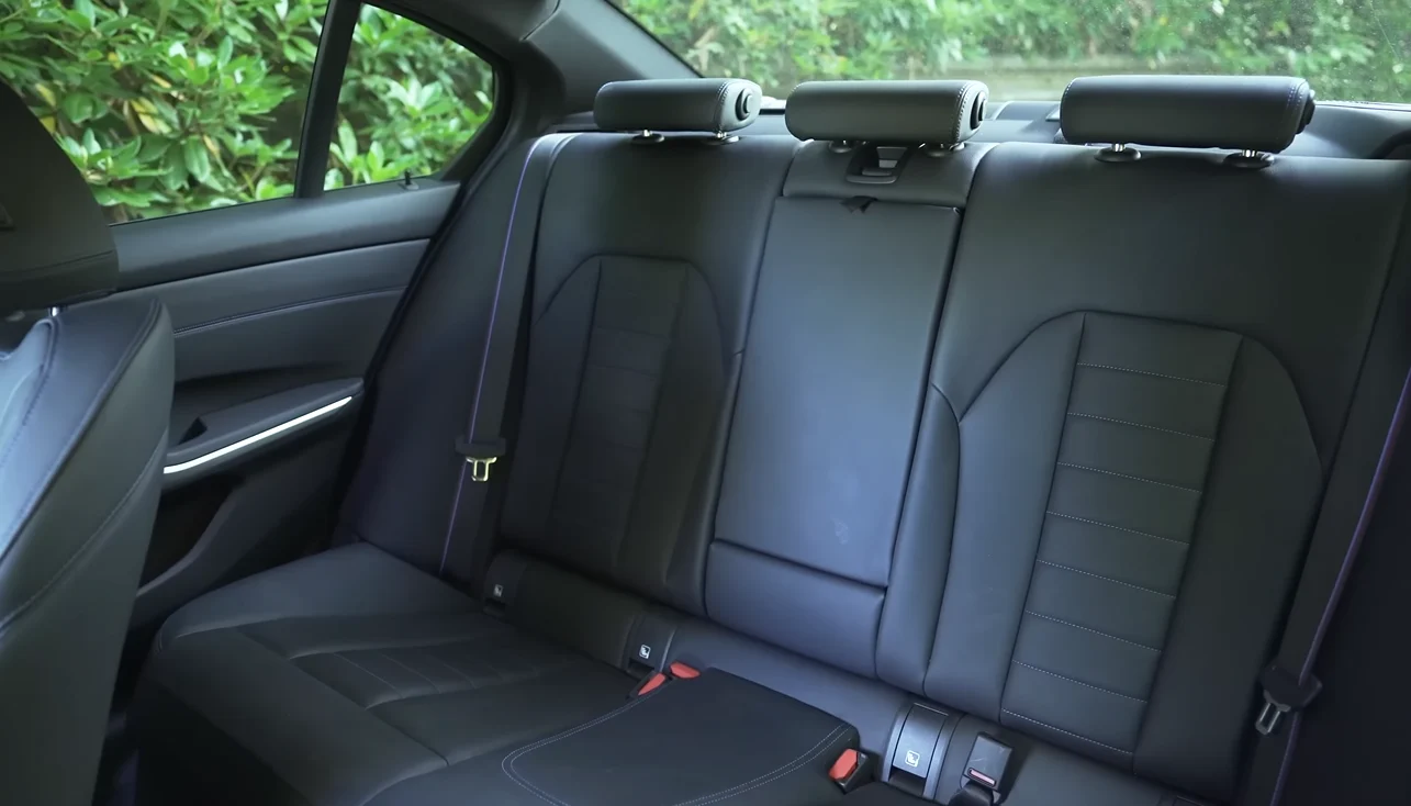 BMW 330i 2026 rear seat space showing sedan passenger room with tight sport seats and 17 cubic feet trunk behind giving family of four practical stroller and sports gear storage