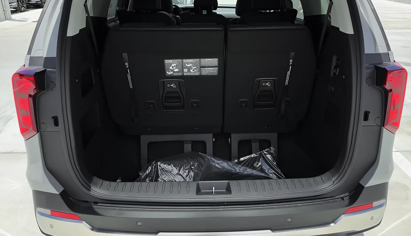 Kia Carnival 2026 cargo space showing 40.2 cubic feet behind third row nearly 8 cubic feet more than Pacifica Hybrid 32.3 cubic feet swallowing strollers bikes and coolers without drama for long road trips