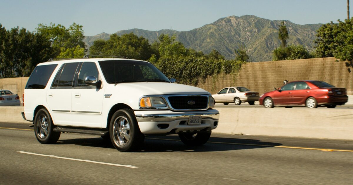 White compact SUV driving on a highway with mountains, illustrative stock photo (not the actual 2026 CR-V or RAV4)