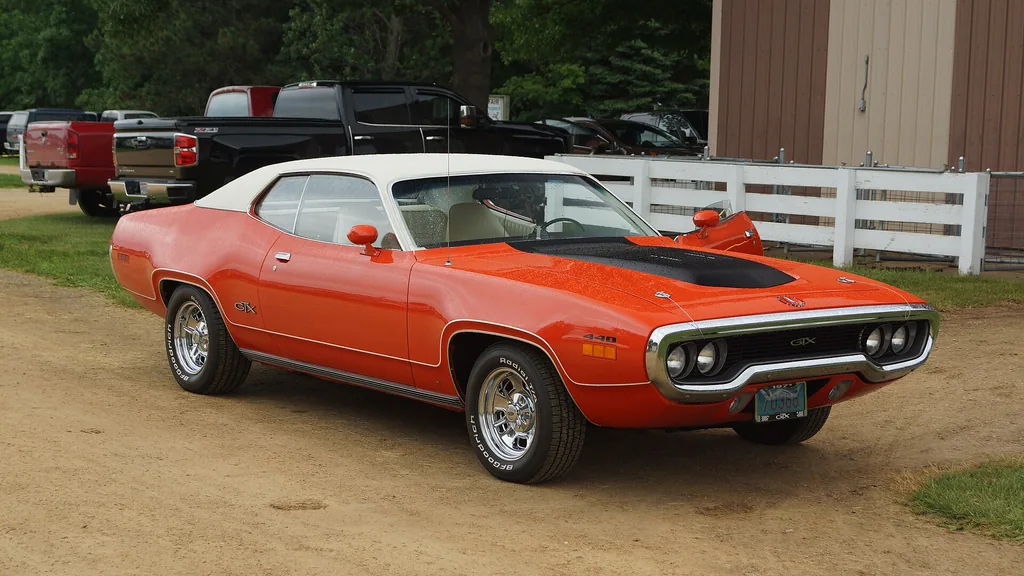 Orange 1971 Plymouth GTX with a white roof at a car show, same model as Dom's black New York car in Fast 8
