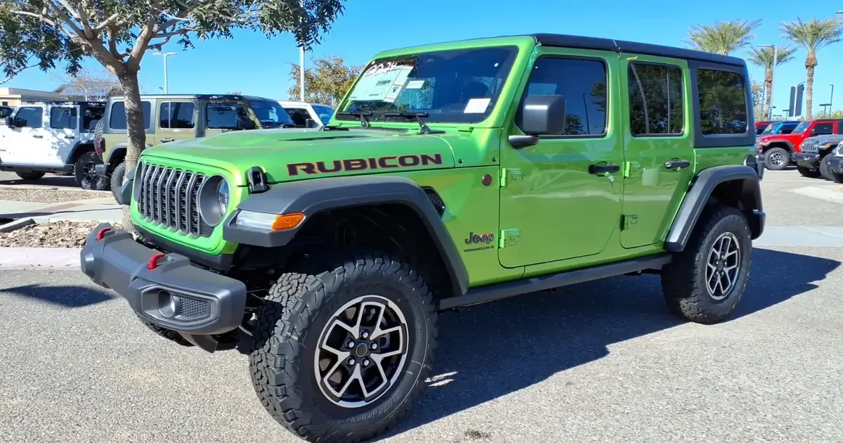 Green 2026 Jeep Wrangler Rubicon 4-door with a black hardtop on a dealer lot in Gilbert, Arizona