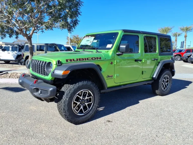 Green 2026 Jeep Wrangler Rubicon 4-door with a black hardtop on a dealer lot in Gilbert, Arizona