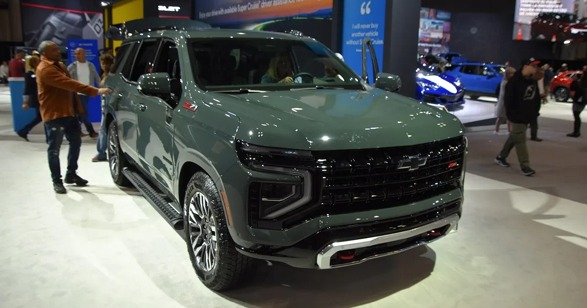 Green Chevrolet Tahoe Z71 with the current front-end design and red recovery hooks on display at an auto show