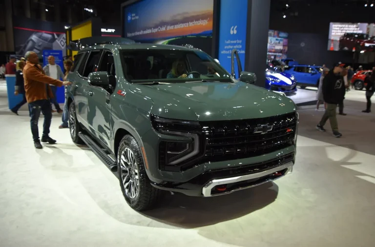 Green Chevrolet Tahoe Z71 with the current front-end design and red recovery hooks on display at an auto show