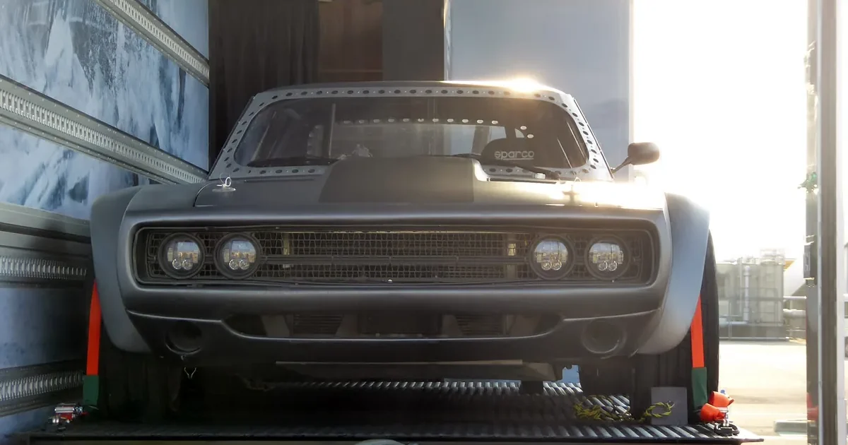 Dom's Dodge Ice Charger from The Fate of the Furious, a matte grey widebody Charger, on display inside a transport trailer