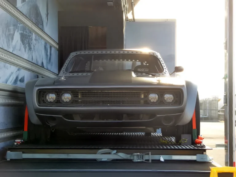 Dom's Dodge Ice Charger from The Fate of the Furious, a matte grey widebody Charger, on display inside a transport trailer