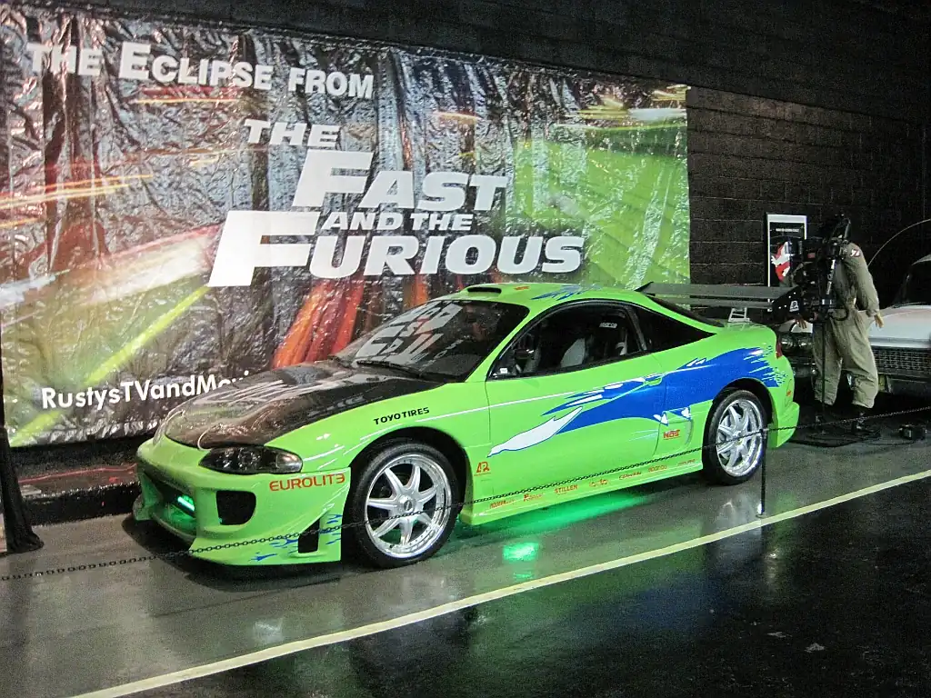 Green Mitsubishi Eclipse with blue graphics displayed in front of a banner reading The Eclipse from The Fast and the Furious at Rusty's TV and Movie Car Museum in Jackson, Tennessee
