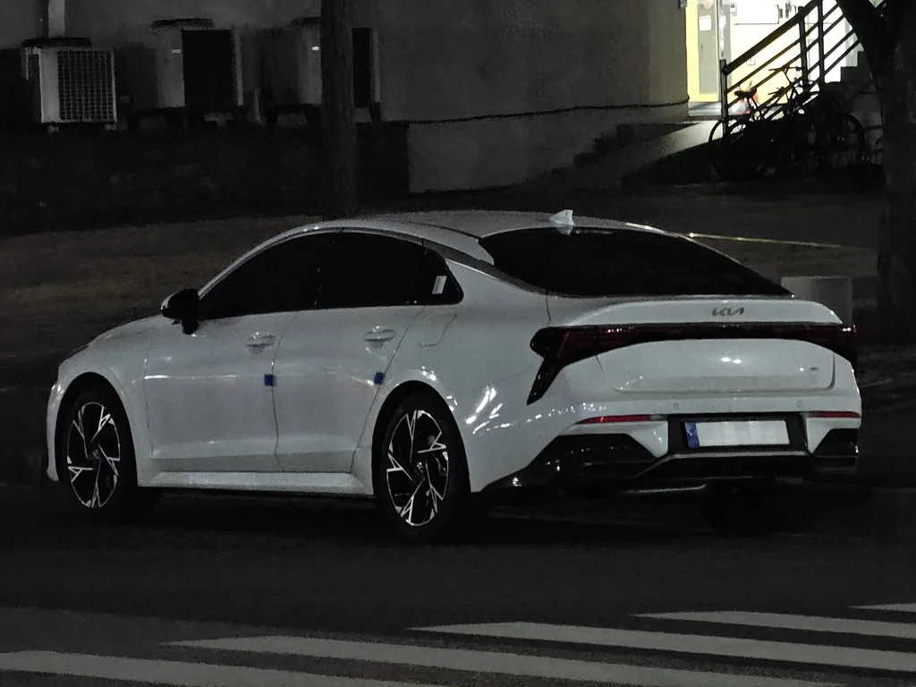 Kia K5 (DL3 facelift / PE) - rear 3/4 exterior, white (evening)