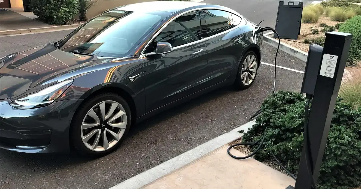 Gray Tesla Model 3 charging at a curbside pedestal charger in Scottsdale, Arizona