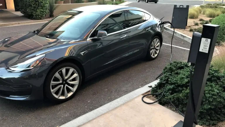 Gray Tesla Model 3 charging at a curbside pedestal charger in Scottsdale, Arizona