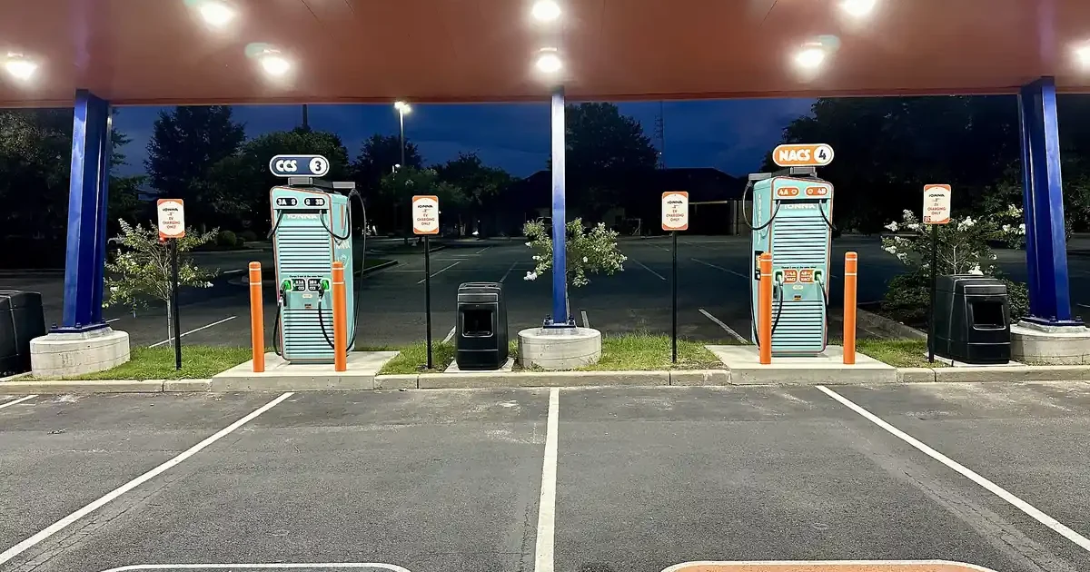 IONNA DC fast charging canopy at night with parking spaces labeled CCS and NACS