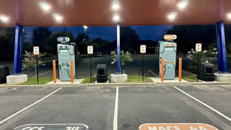 IONNA DC fast charging canopy at night with parking spaces labeled CCS and NACS