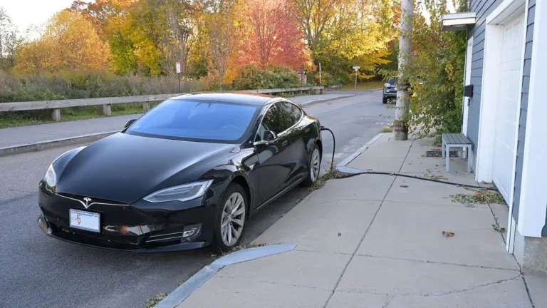 Black Tesla Model S parked at a curb and plugged into a charger at a home in Dorchester, Boston