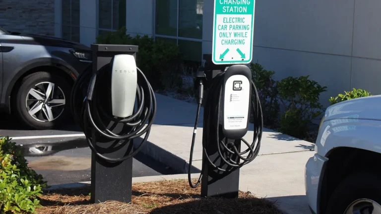 Two Level 2 EV charging pedestals with J1772 cables beside a hotel parking space marked for electric car charging