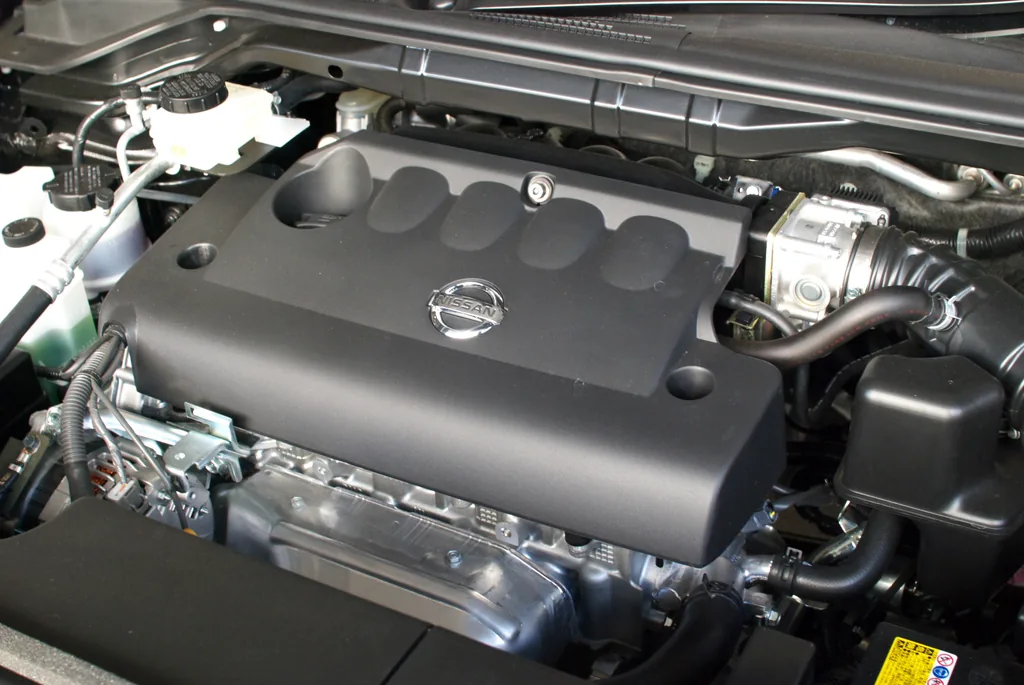 Nissan QR25DE 2.5-liter four-cylinder engine under the hood, with the silver electronic throttle body visible at the right end of the intake