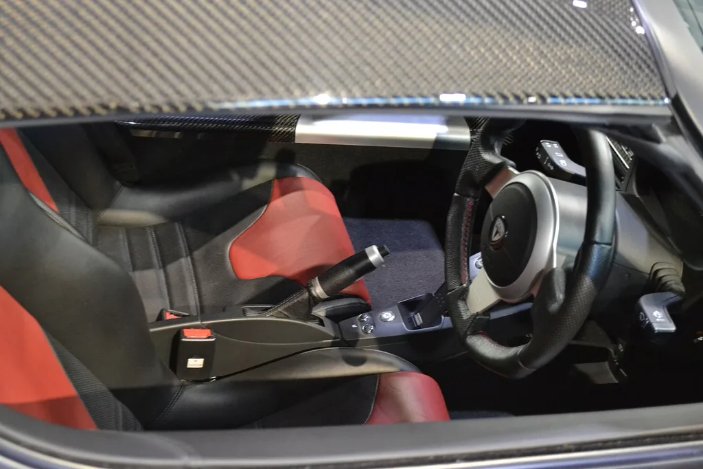 Cabin of a right-hand-drive 2010 Tesla Roadster 2.5 Sport with black and red seats, on display at the Toyota Automobile Museum