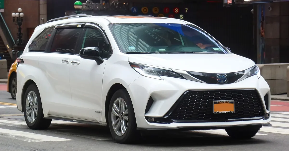 White 2021 Toyota Sienna XSE Hybrid minivan, front three-quarter view, on a city street in Midtown Manhattan