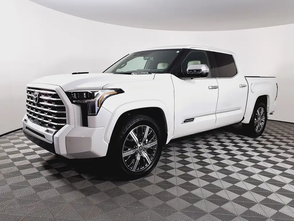 White 2023 Toyota Tundra Capstone hybrid CrewMax with chrome grille and 22-inch wheels in a dealer photo booth